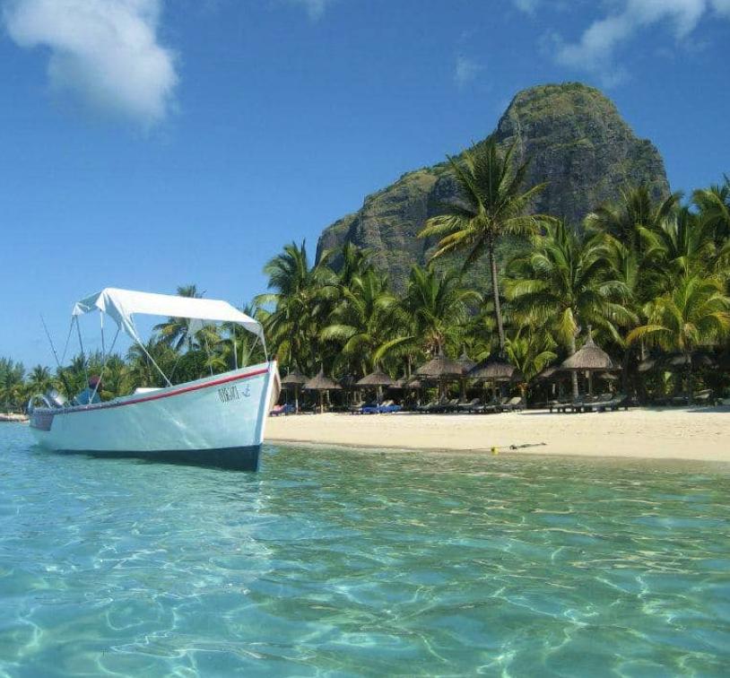 A small boat moored next to a tropical island, sunshine