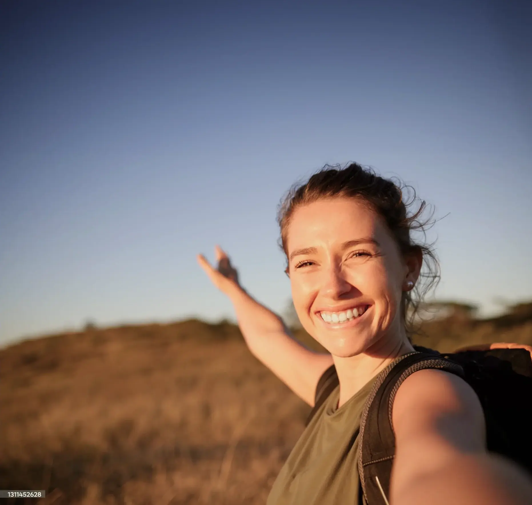 Woman in the sunshine, smiling and pointing to the distance